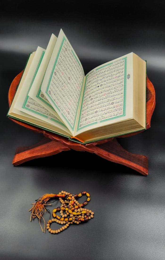 Services An open Quran on a wooden stand with prayer beads symbolizes devotion and worship.